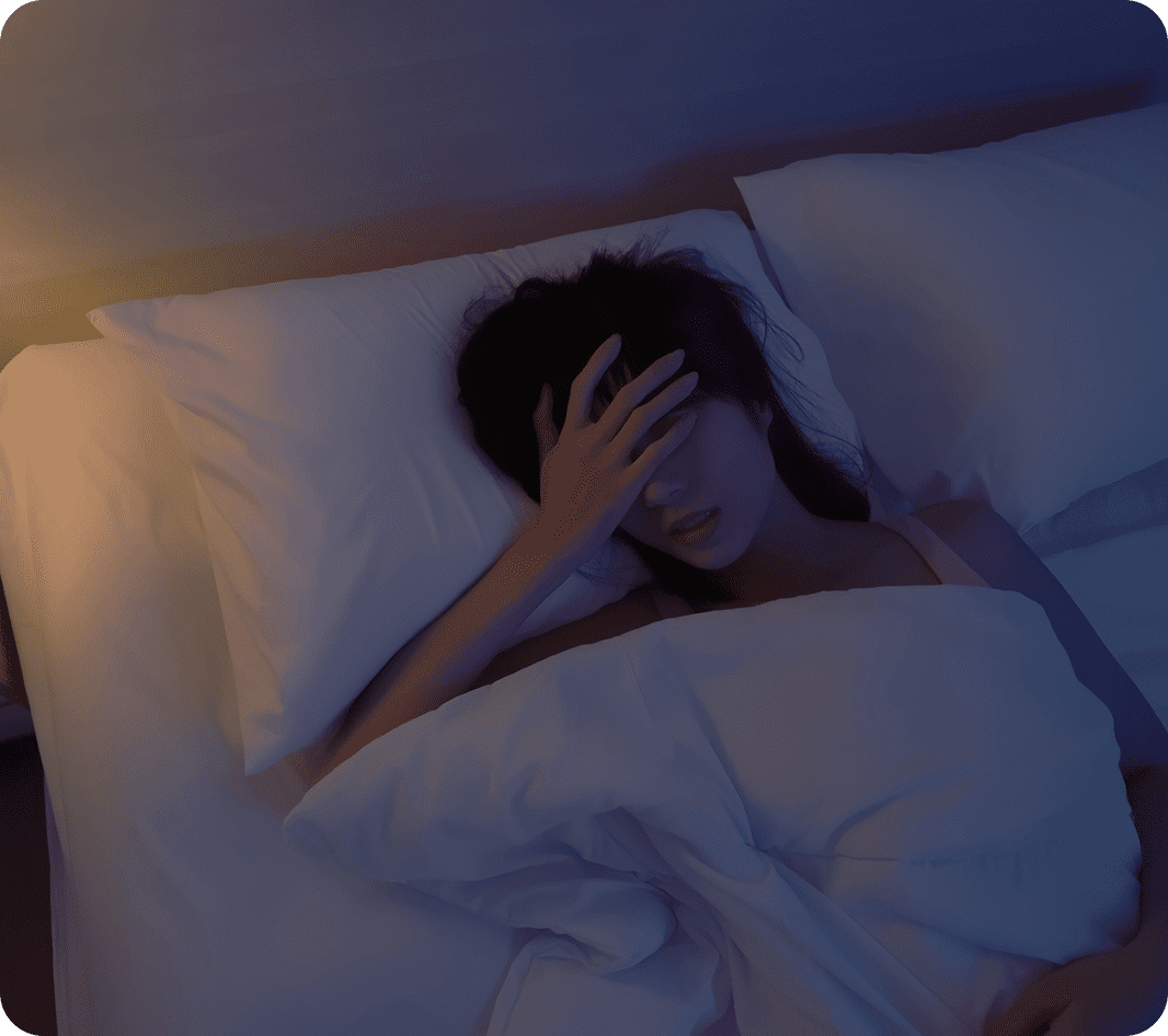 Person lying in bed, covering their face.